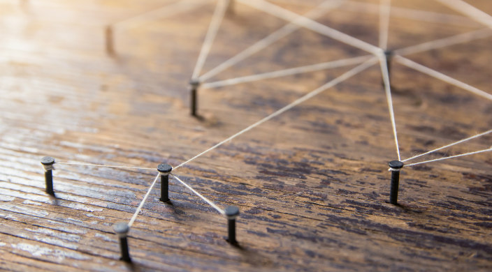 Pegs in a wooden board connected by white thread